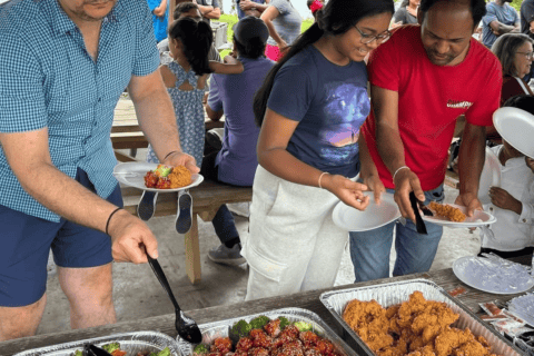International students serve themselves food during an outdoor summer picnic hosted by the International Student Council at an Evergreen Park pavilion.