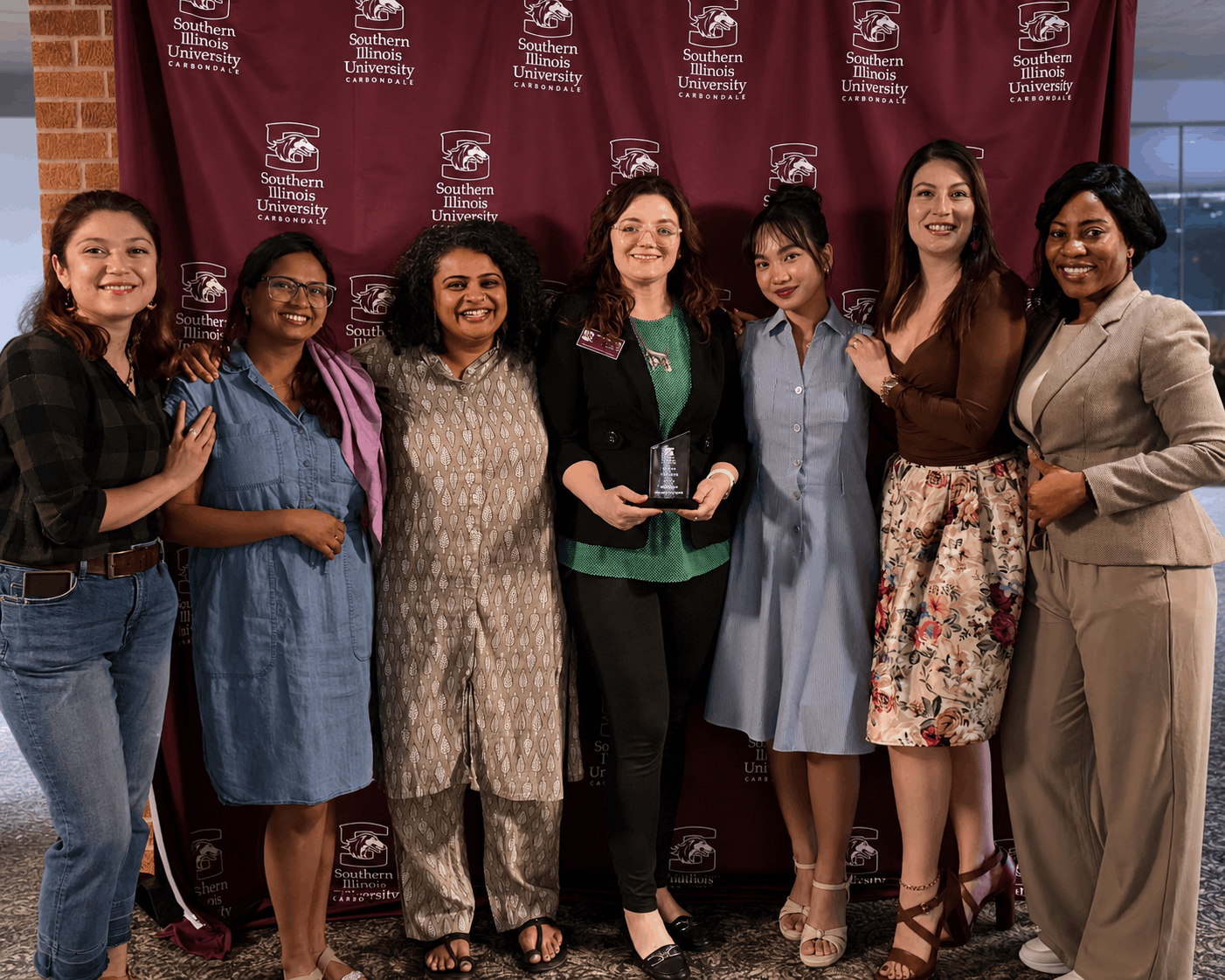 Members of the Multicultural Empowered Women Student Association (MEWSA) Academic Year 2025 - 2026 pose for a group photo at an awards ceremony while holding an award plaque for RSO of the Year.
