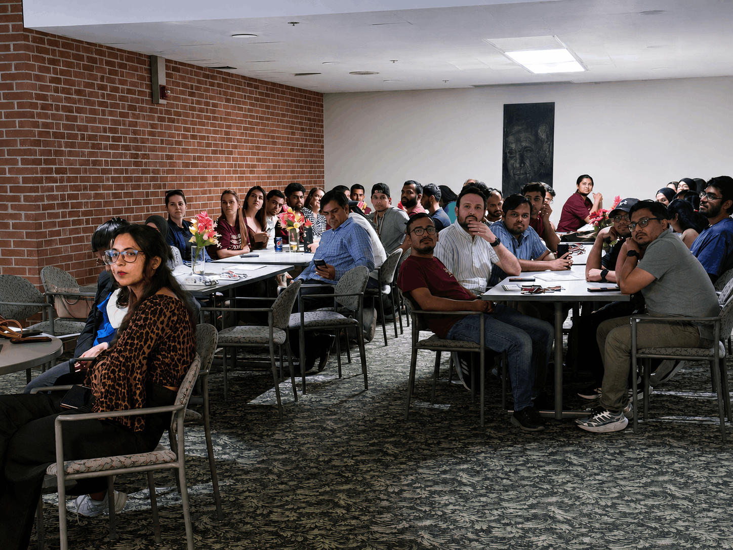 Students, scholars, and community members sit together at tables during the International Student Council Spring Feast 2026 gathering in the Student Center at SIU Carbondale. Attendees face the front of the room and listen to a presentation.